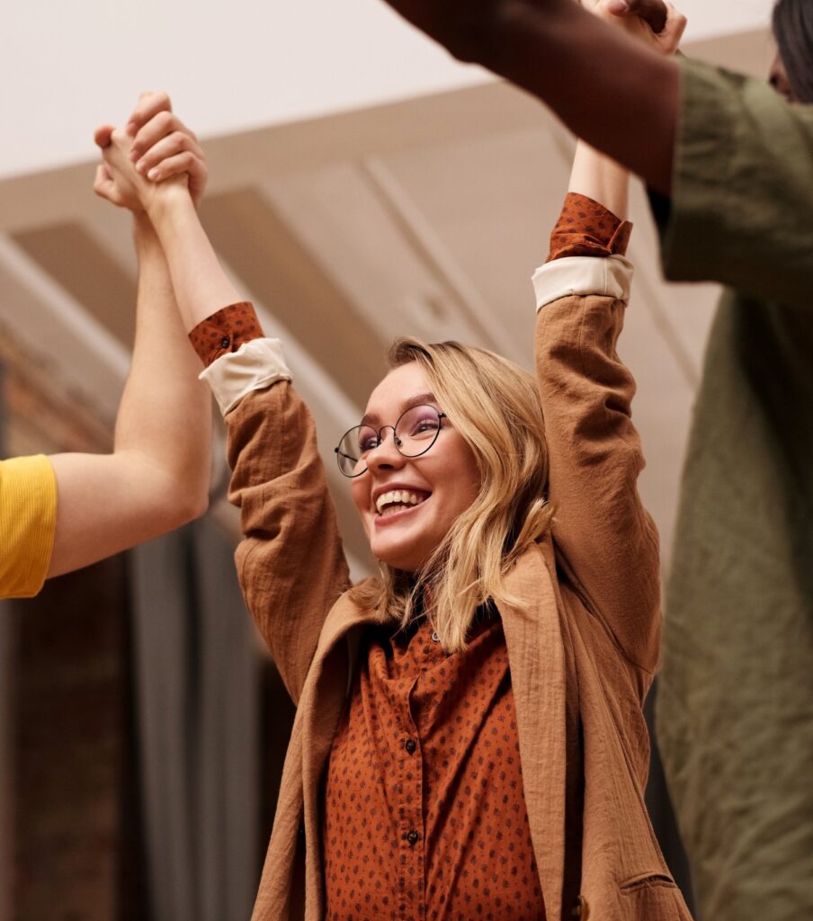 A woman raises her hands high with her colleagues.