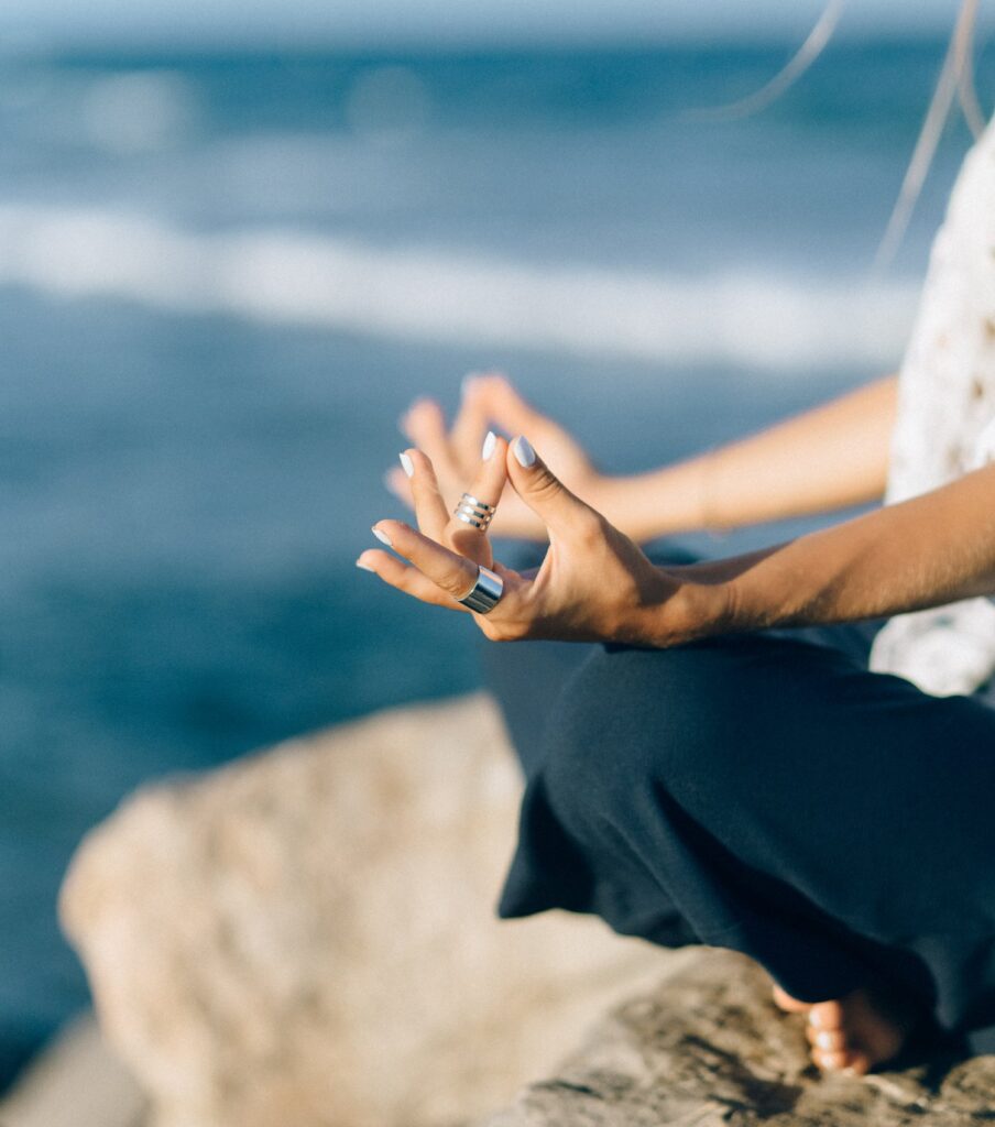 A woman meditates by the sea.